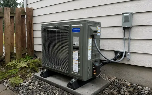 Central air conditioning condenser on a concrete pad beside a Puyallup, WA home