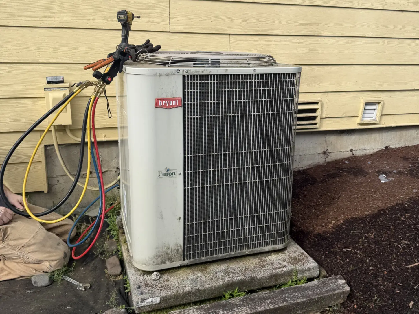 Heat pump service in Puyallup, WA: Pinnacle Air Control technician checking refrigerant pressures on a Bryant outdoor unit